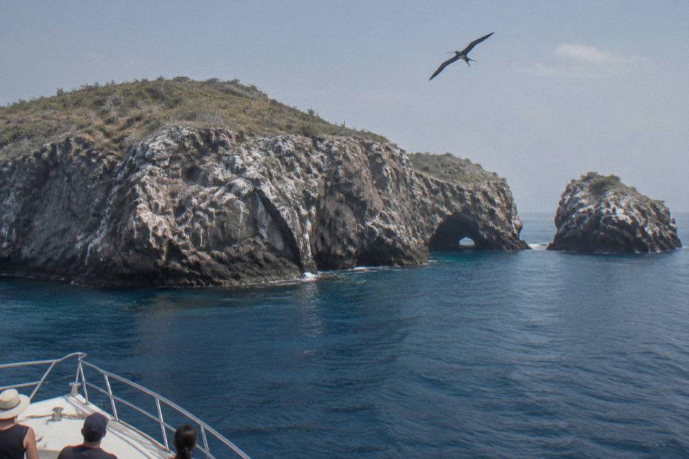Rocky cliffs of an island rising from calm blue bay water
