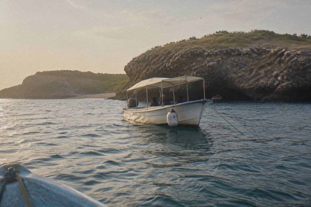 A small covered boat anchored near rocky cliffs at the Marietas Islands