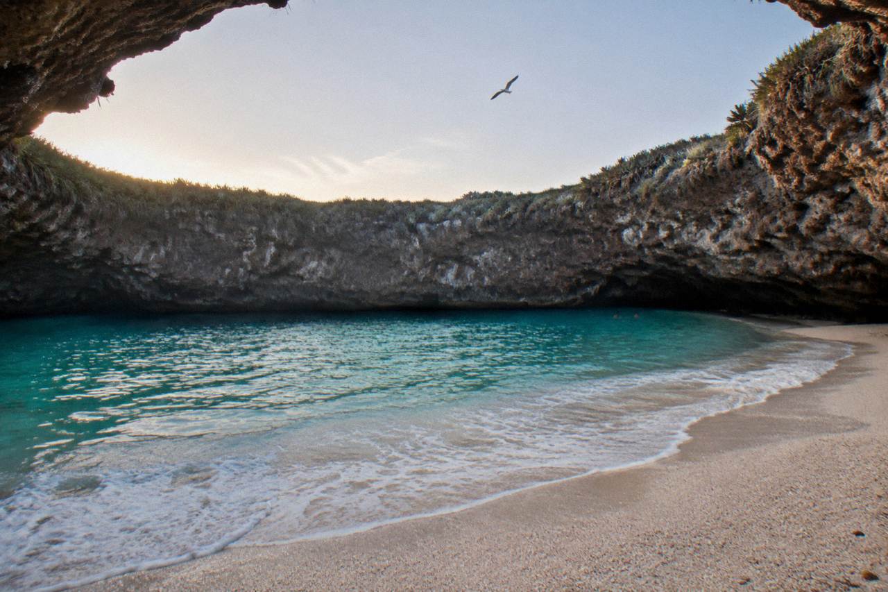 A crater beach ringed by rock walls with turquoise water inside the Marietas Islands