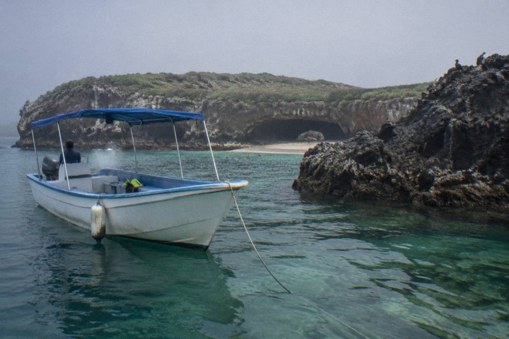 Snorkel boat anchored near rocky shoreline with clear shallow water
