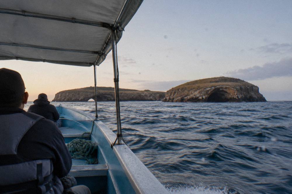 A small boat approaching the rocky islands of the Marietas archipelago on open water