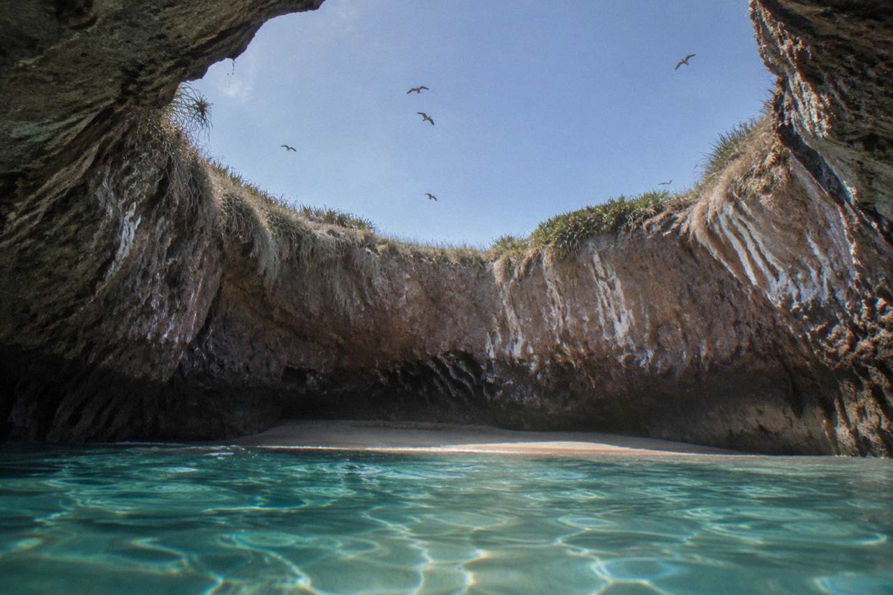 A crater beach inside a rocky island opening seen from the water at the Marietas Islands