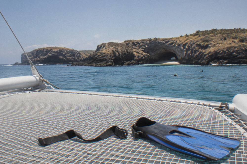 A wide catamaran deck with netting at the bow under an open sky