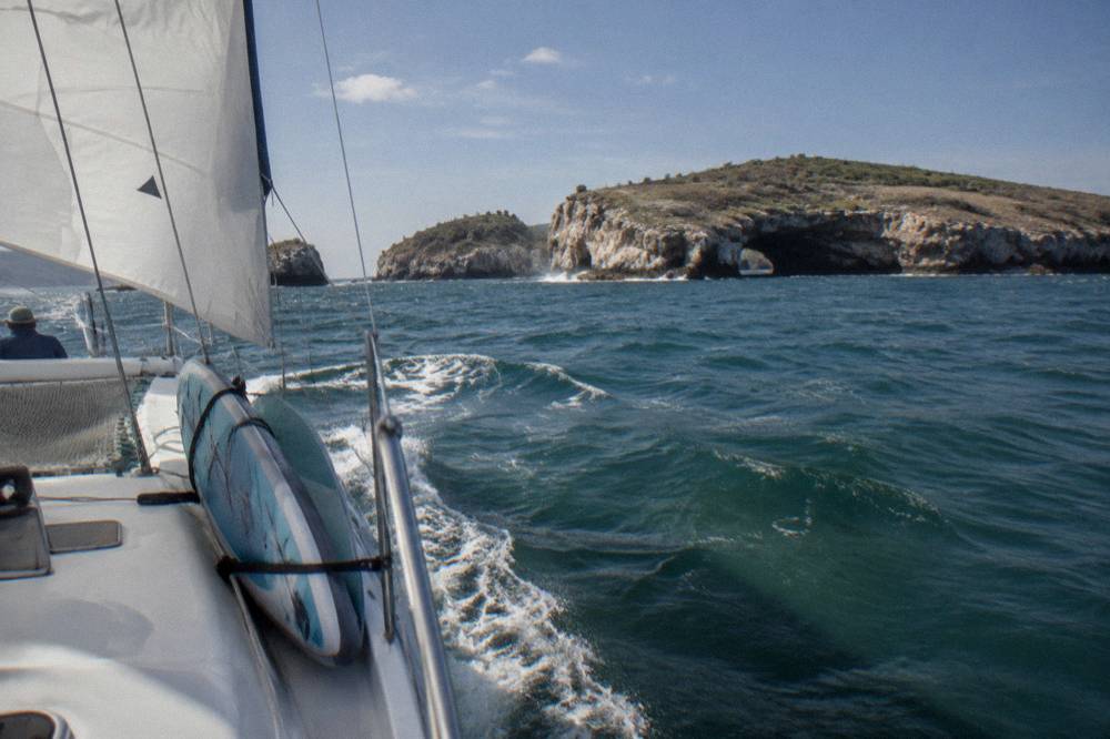 A small sailing catamaran under way on open water near the coast