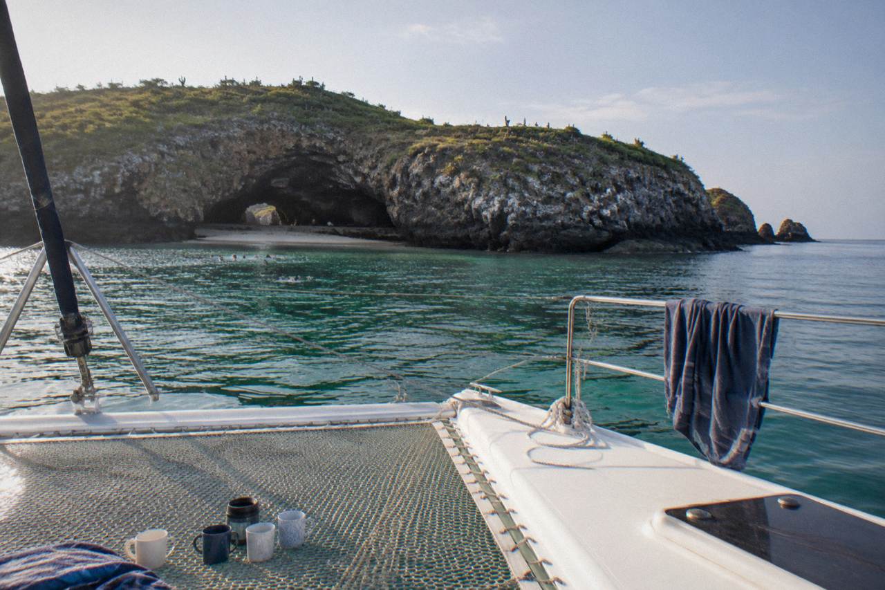 A catamaran anchored near the rocky islands of the Marietas archipelago on calm water