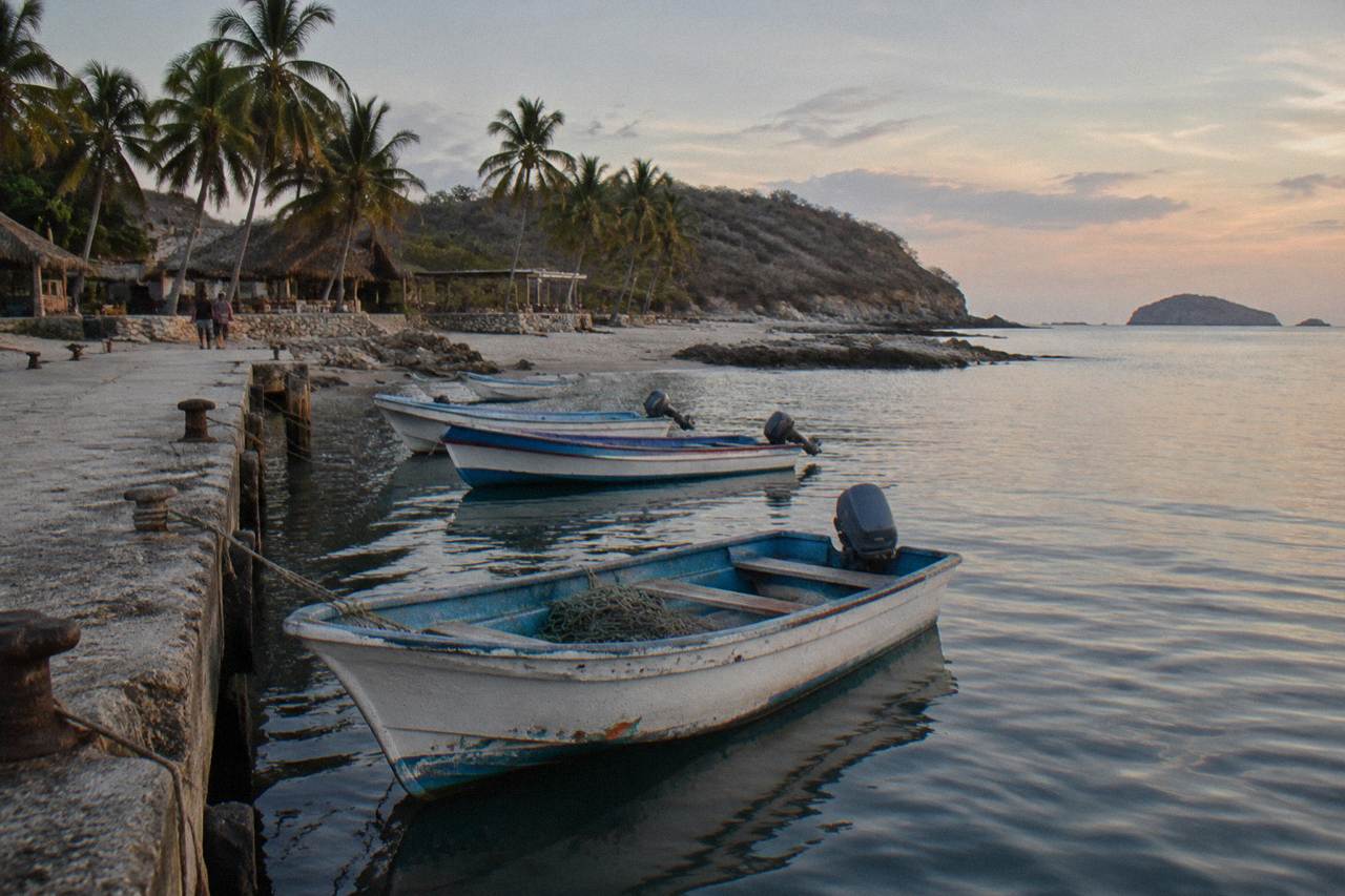 Fishing boats moored in calm water at a small pier on the Punta de Mita coastline