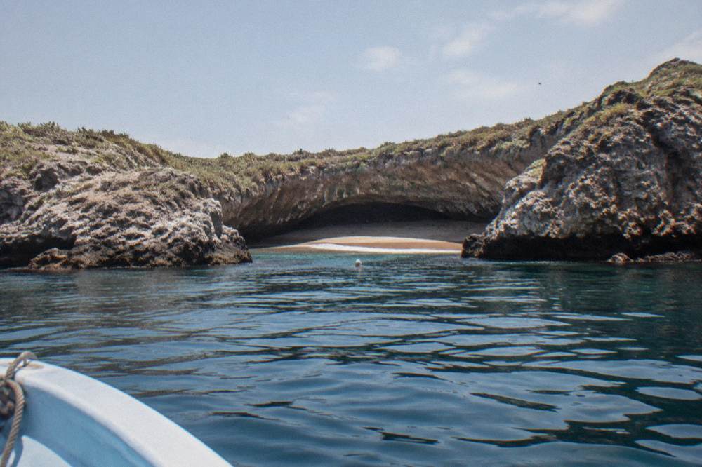 The crater opening of a hidden beach seen from the water with rocky cliffs around it