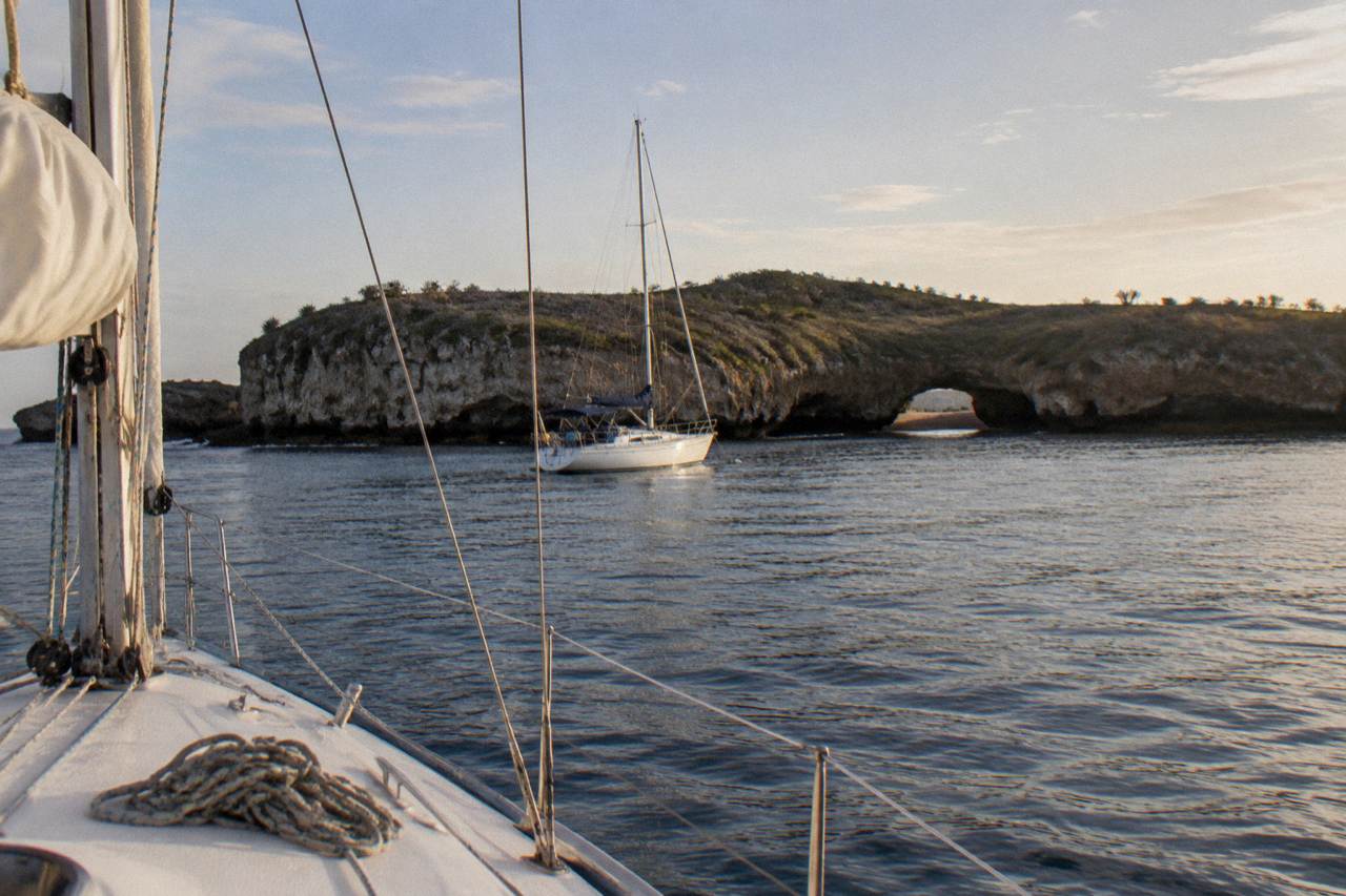 Sailboat anchored off the Marietas Islands with rocky cliffs rising from calm Pacific water