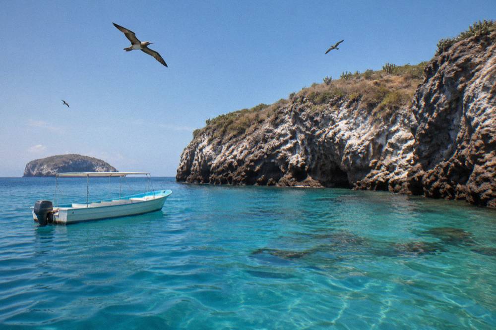 Snorkel boat anchored near rocky islands with clear shallow water