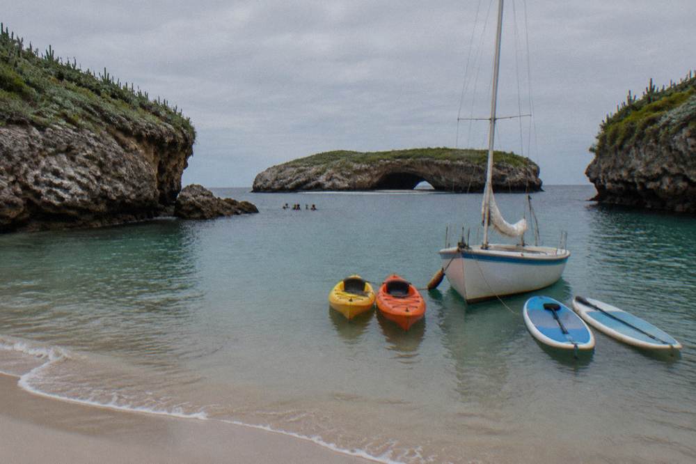 Kayaks and paddleboards tied alongside a boat in a calm cove