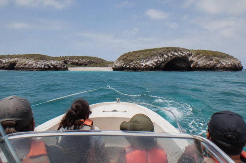 A private motorboat cruising toward steep rocky cliffs above clear turquoise water