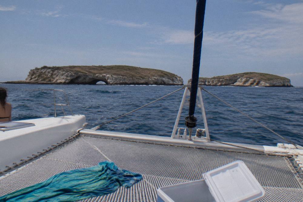 A catamaran cruising across open water toward islands on the horizon
