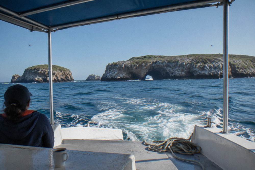 A covered small boat crossing open water toward distant island silhouettes