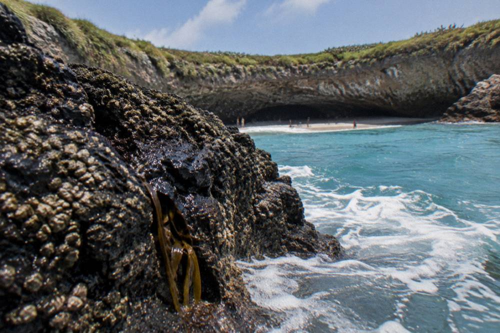 Turquoise water breaking against dark volcanic rock formations
