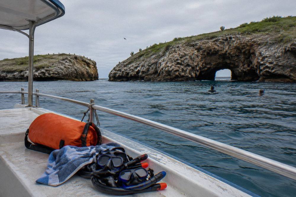 Snorkel masks, snorkels, a towel and an orange duffel bag on a boat bench